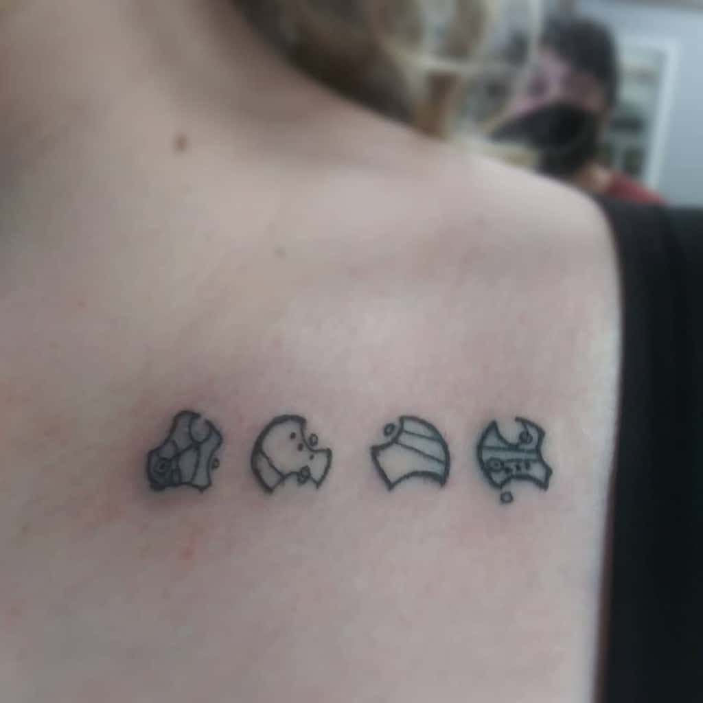 Minimalist black ink tattoo featuring four small, iconic symbols from 'Doctor Who', arranged in a line