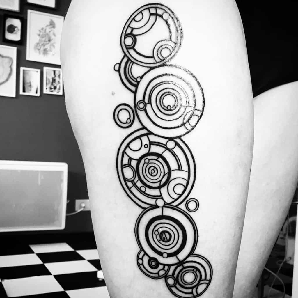 Striking black and white tattoo featuring Gallifreyan script from 'Doctor Who', composed of various interconnected circular designs