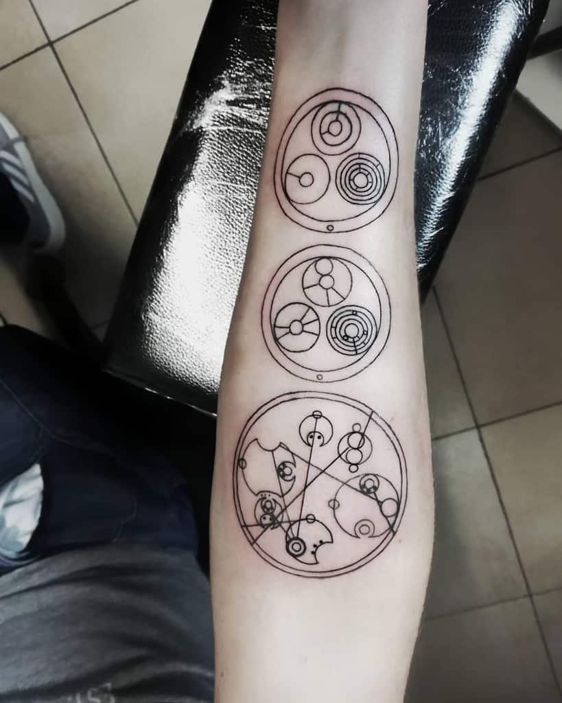 Linear tattoo, displaying three vertical Gallifreyan symbols from 'Doctor Who', each within a separate circle, rendered in a clean, minimalistic style