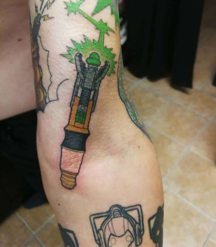 Colorful Doctor Who tattoo featuring a Sonic Screwdriver emitting green energy bursts, surrounded by abstract designs