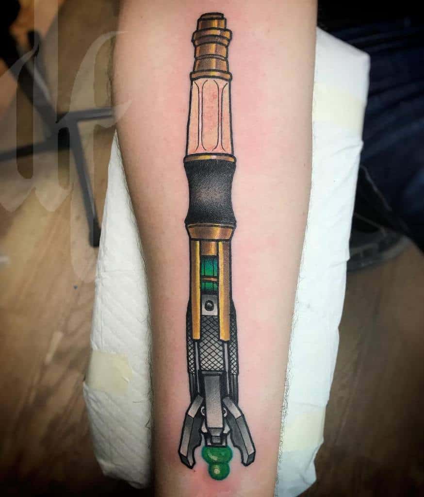 Elaborate tattoo of the Doctor Who Sonic Screwdriver with detailed linework, showing various textures and a green crystal tip