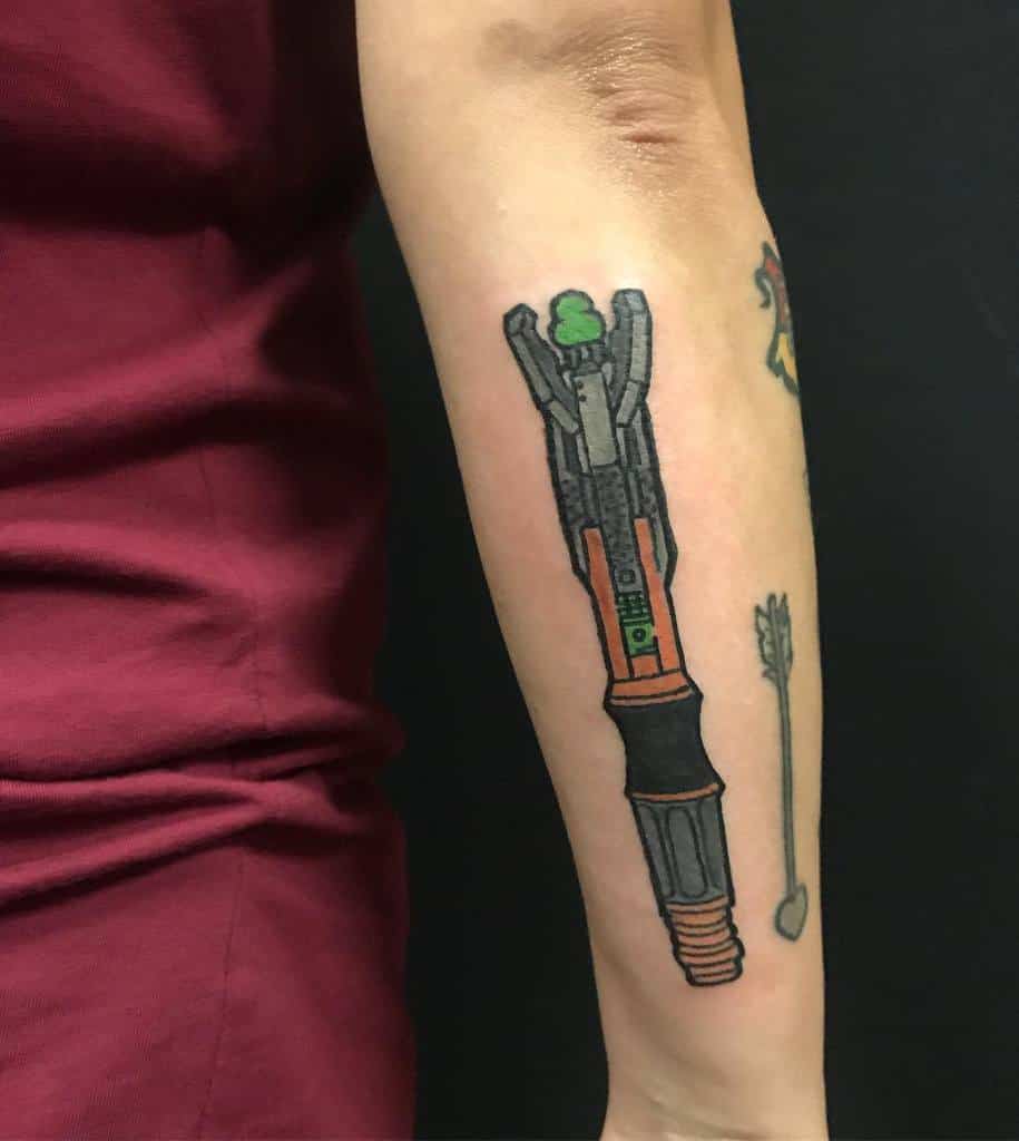 Doctor Who tattoo featuring a Sonic Screwdriver with a glowing green tip and a symbolic arrow with a heart