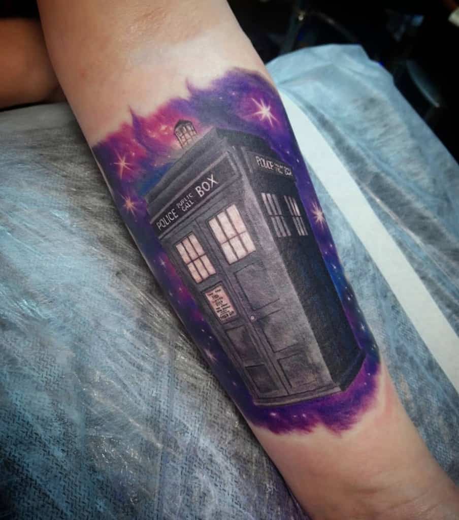 Striking Doctor Who tattoo of the TARDIS against a cosmic background with vivid purple and blue nebulae and sparkling stars