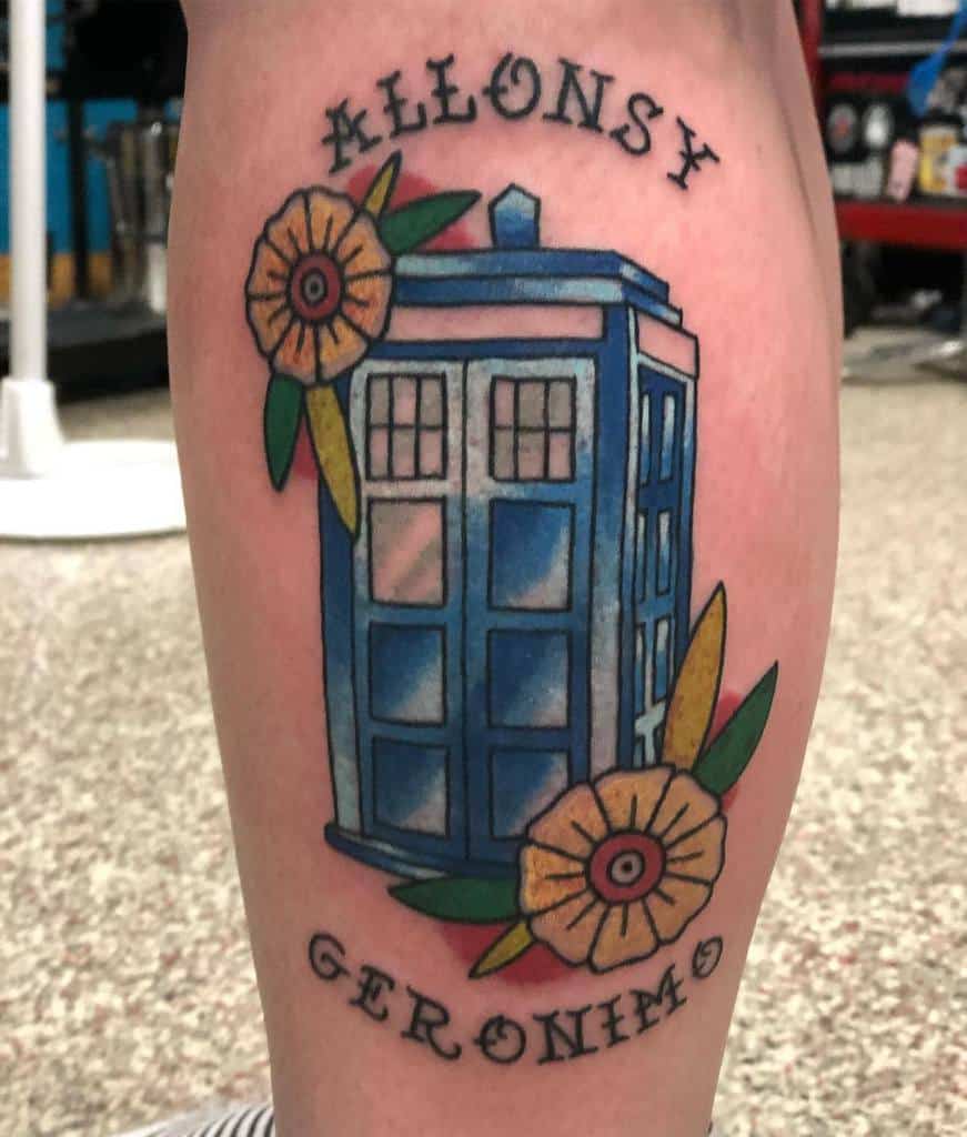 Doctor Who tattoo featuring the TARDIS surrounded by flowers, with 'Allonsy' and 'Geronimo' written above and below in bold lettering