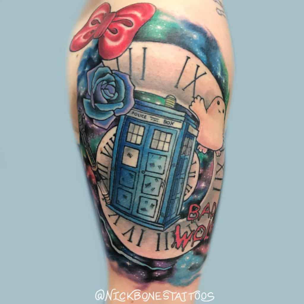 Doctor Who tattoo featuring the TARDIS over a Roman numeral clock, a blue rose, a red bow, a ghost, and 'Bad Wolf' in red graffiti