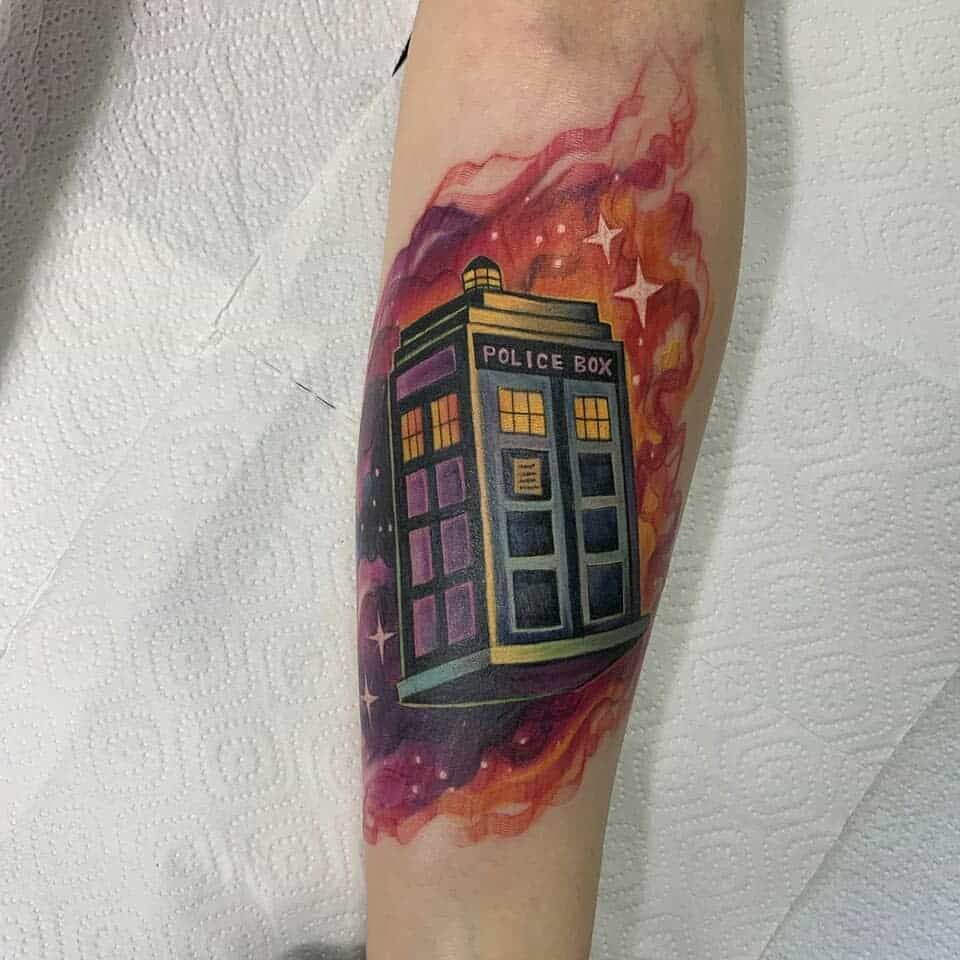 Doctor Who tattoo featuring the TARDIS surrounded by a fiery cosmic nebula with glowing stars, blending deep purples, reds, and oranges
