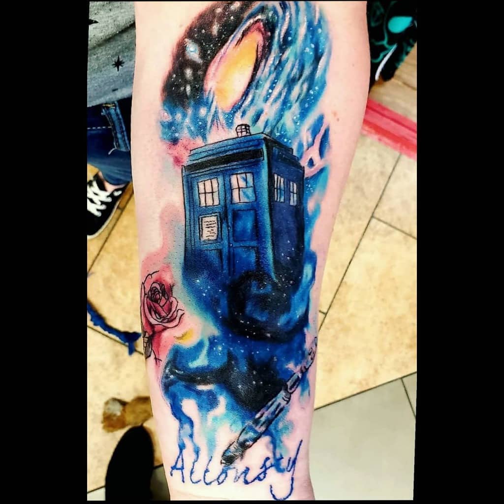Doctor Who tattoo featuring the TARDIS in a swirling blue galaxy, a Sonic Screwdriver, a red rose, and 'Allonsy' scripted in flowing text