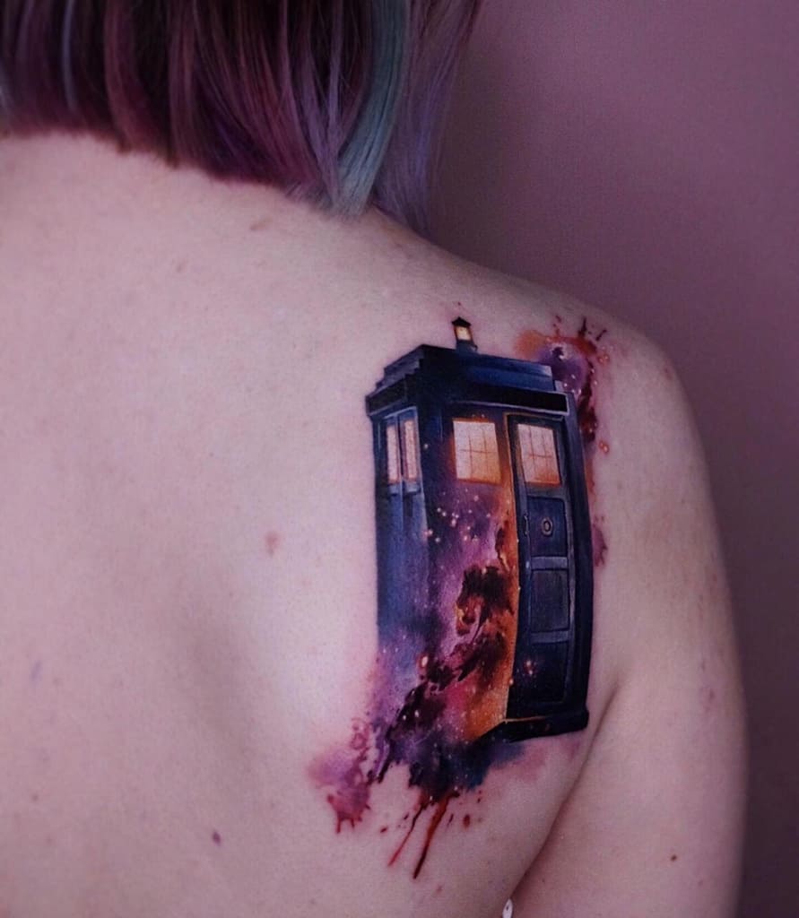 Colorful tattoo of the TARDIS from Doctor Who, depicted with a cosmic watercolor effect, blending into a galaxy-inspired background
