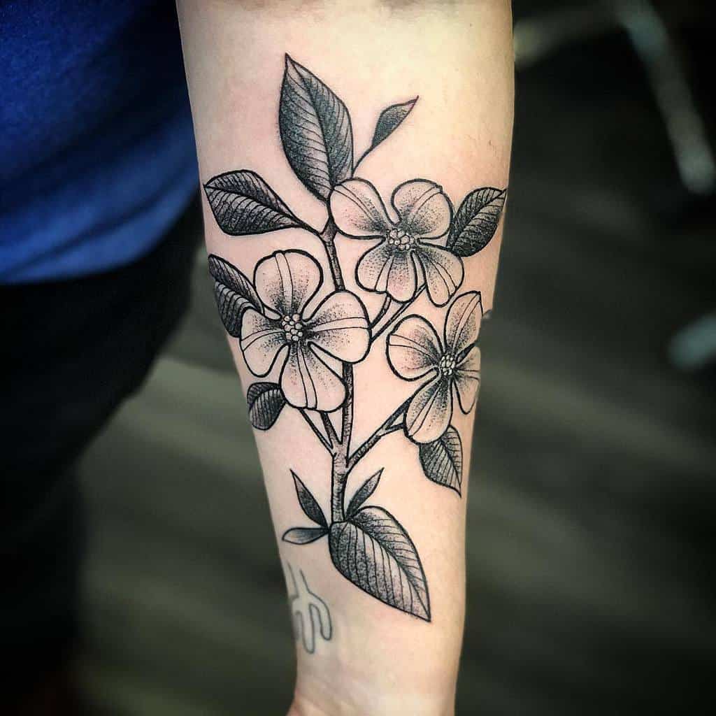Forearm tattoo of detailed black and white dogwood flowers with leaves