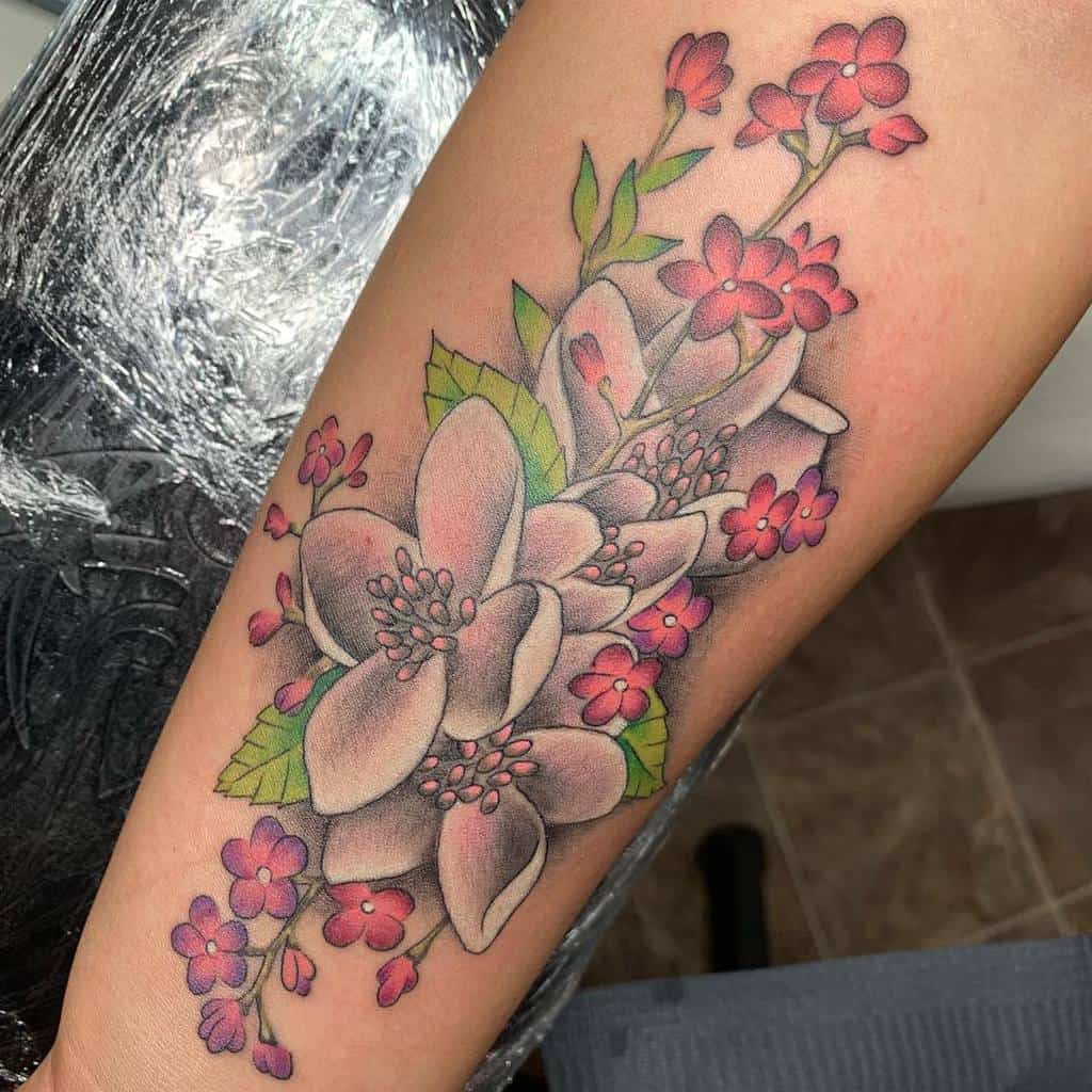 A vibrant tattoo of dogwood blossoms with pink and white flowers, complemented by lush green leaves, elegantly wraps around an arm