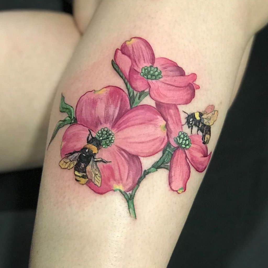 Tattoo of delicate pink dogwood flowers with green centers, accompanied by buzzing bees