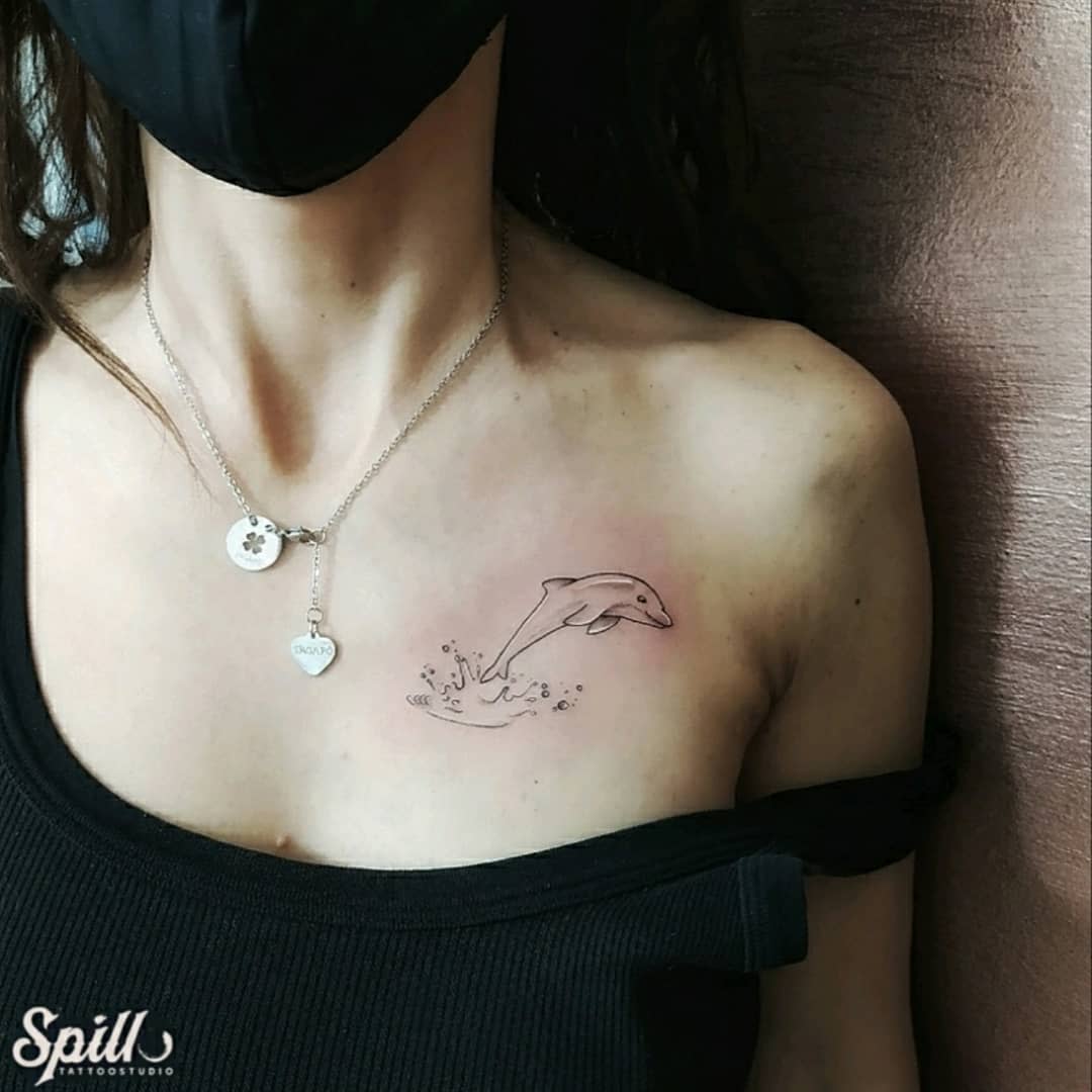 Woman with a dolphin tattoo on her collarbone