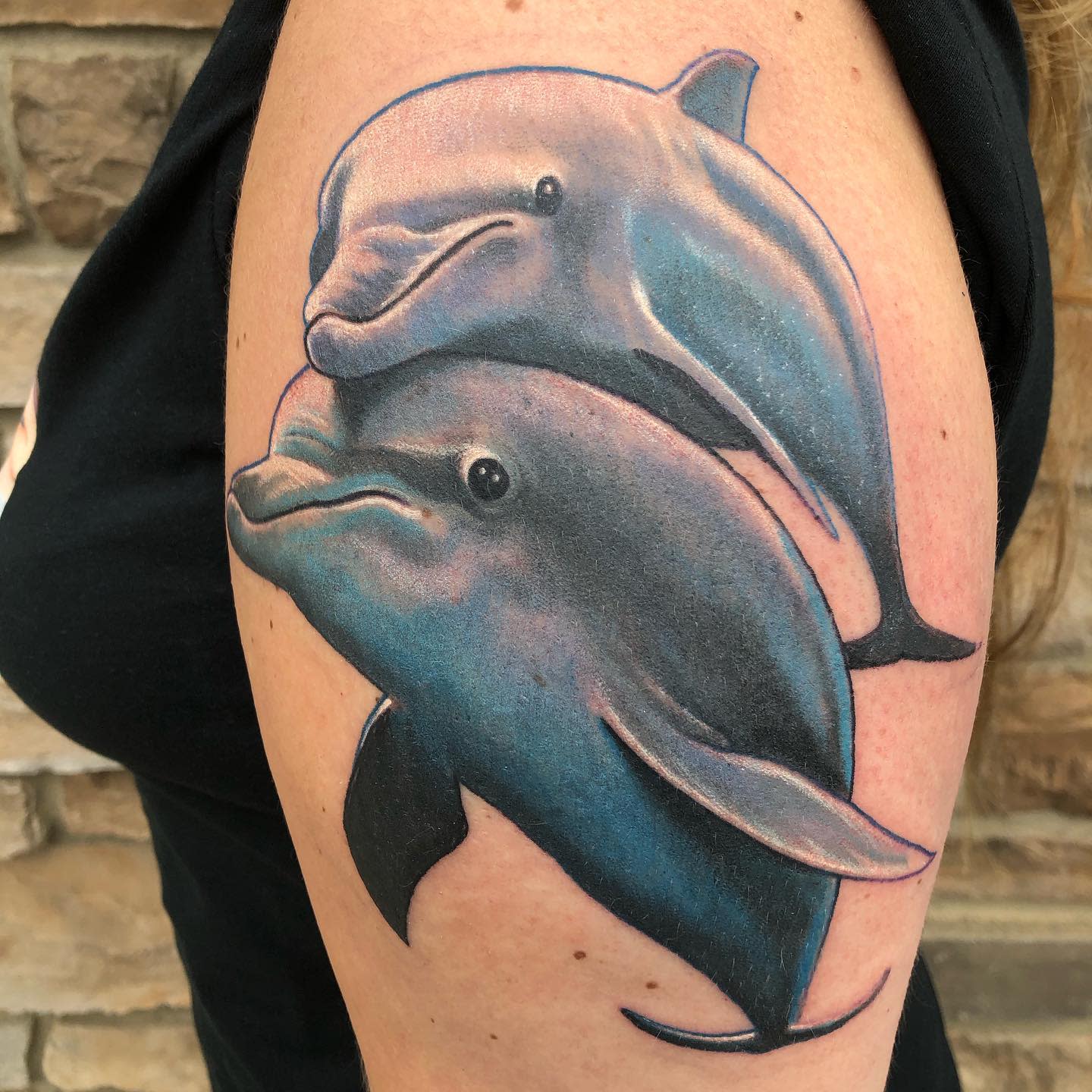 Tattoo of two dolphins on an upper arm