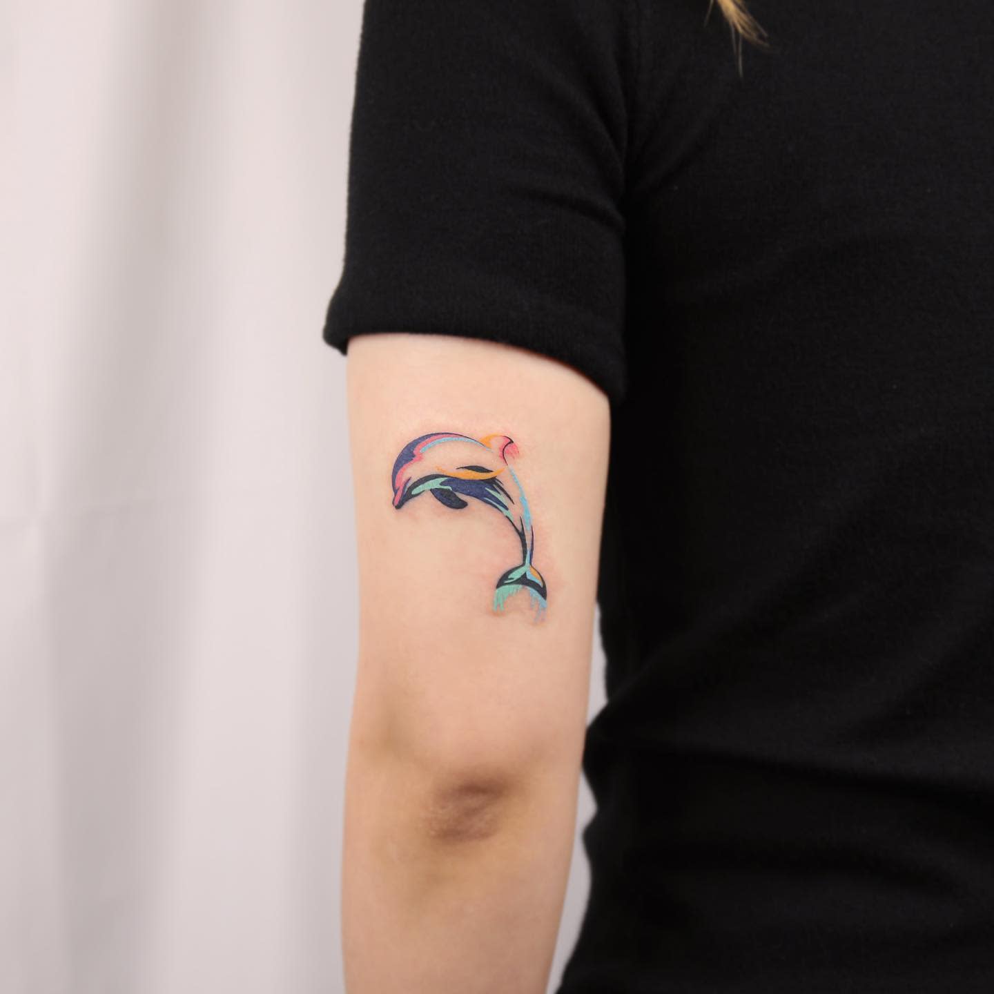 Colorful dolphin tattoo on upper arm