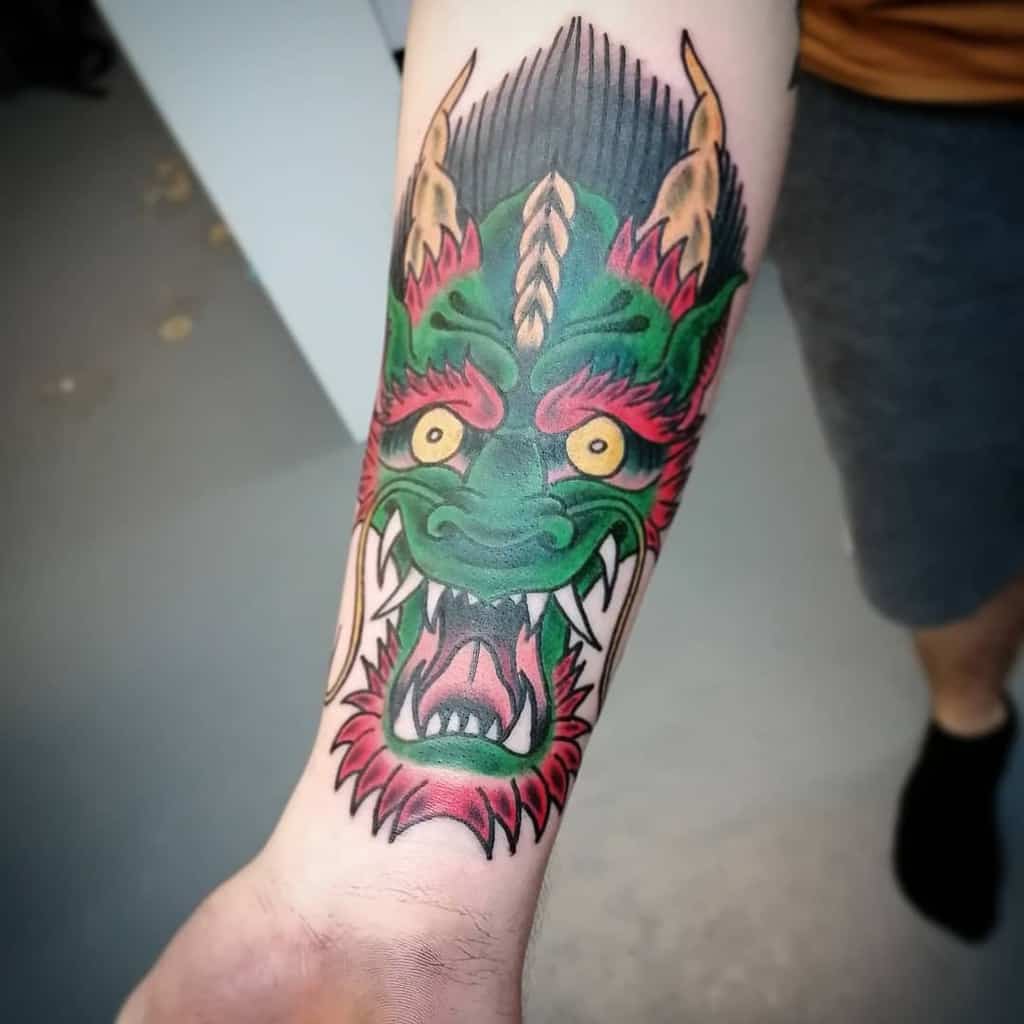 A vibrant dragon tattoo gracefully coils around a person's forearm, its head adorned with intricate green, red, and yellow details