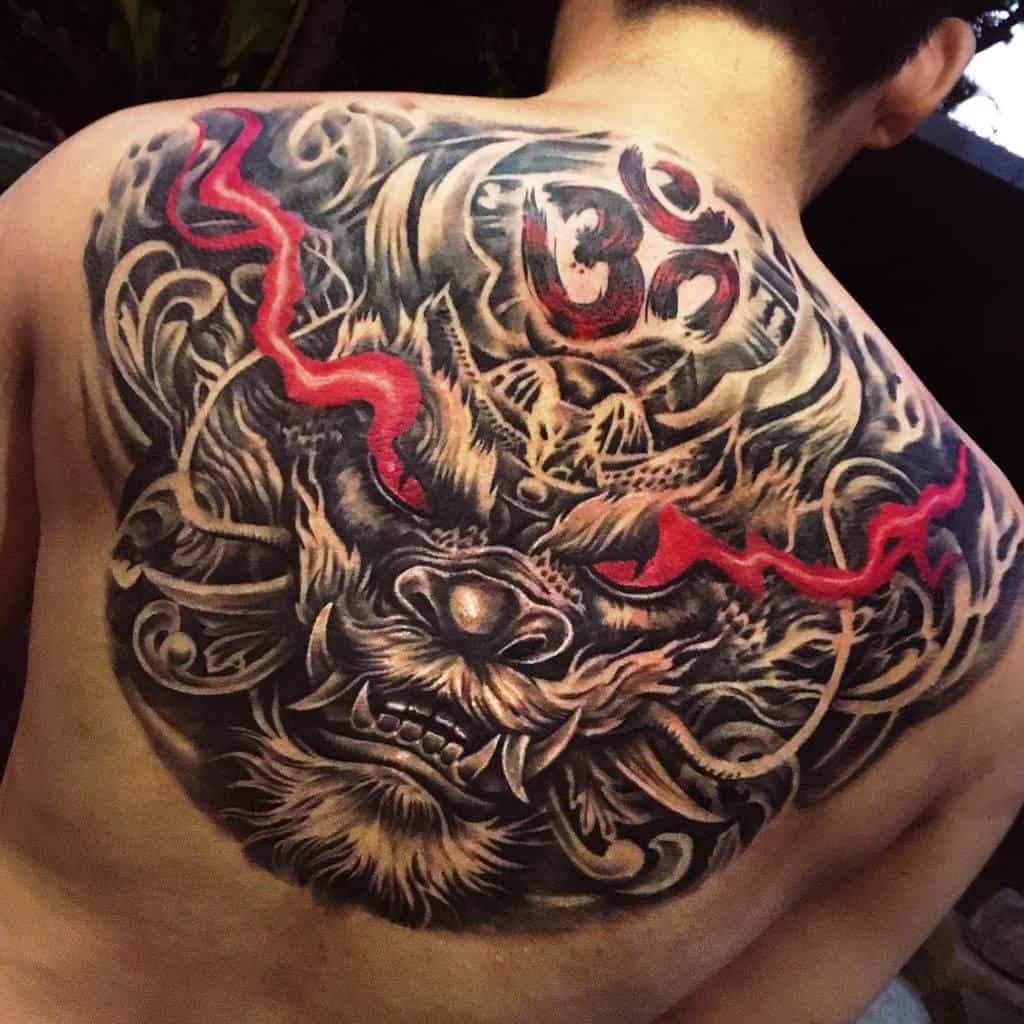 A striking back tattoo featuring the head of a fierce dragon, accentuated with vivid red details and an Om symbol