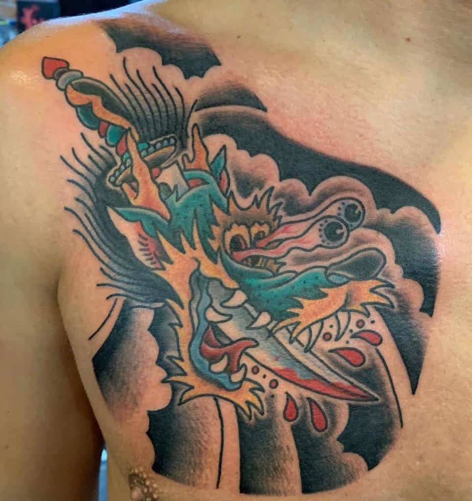 A vibrant dragon head tattoo with a dagger is artfully inked on the person's chest