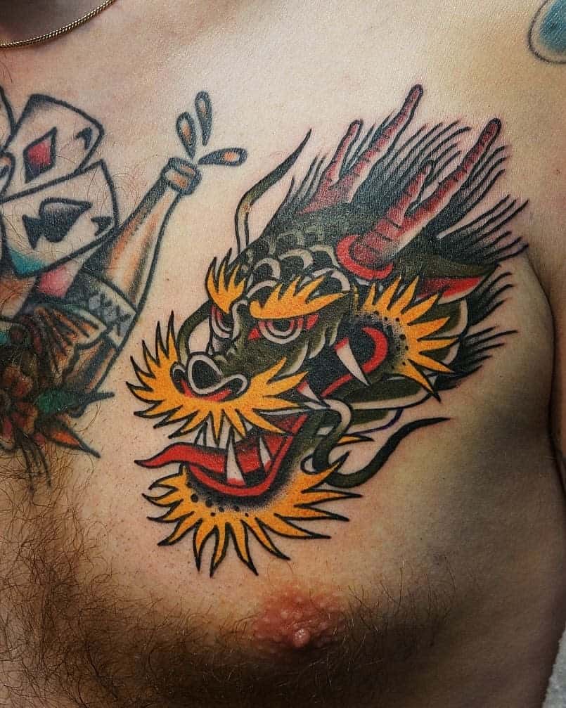 A colorful dragon tattoo graces a person's chest, with bold lines and vibrant hues, the creature's head artfully sweeping across the skin