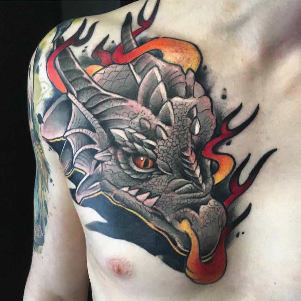 A vibrant chest tattoo showcases a dragon head engulfed in flames, blending bold colors with striking detail