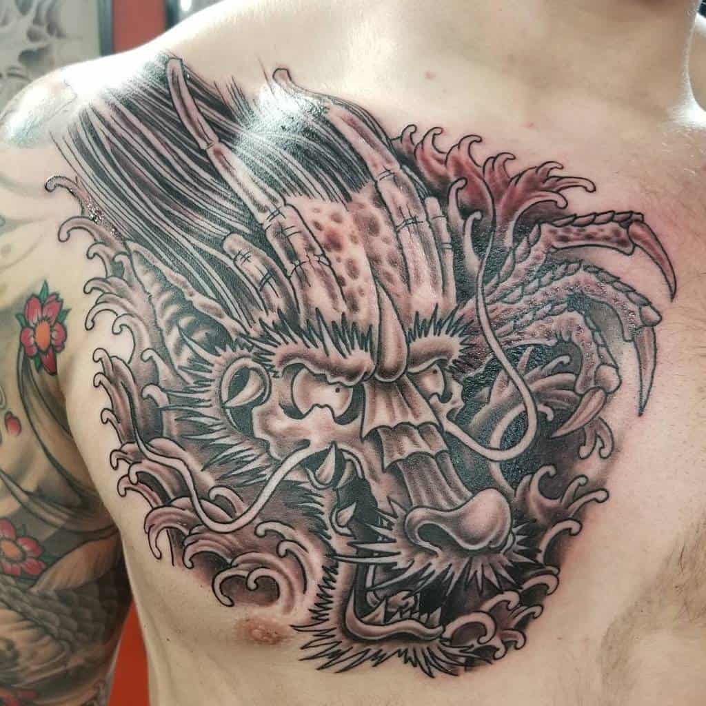 A chest tattoo featuring a fierce dragon, intricately detailed from head to tail, with stylized flames and expert shading