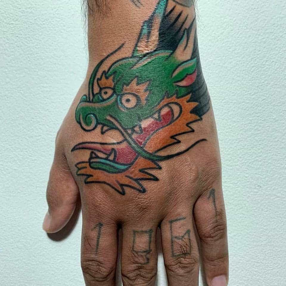 A vibrant hand tattoo showcases a colorful dragon head, intricately designed with the numbers 1961 elegantly splayed across the fingers