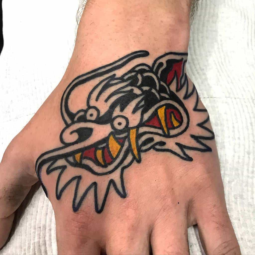 A striking hand tattoo featuring the fierce head of a stylized dragon, rendered in bold black, red, and yellow ink