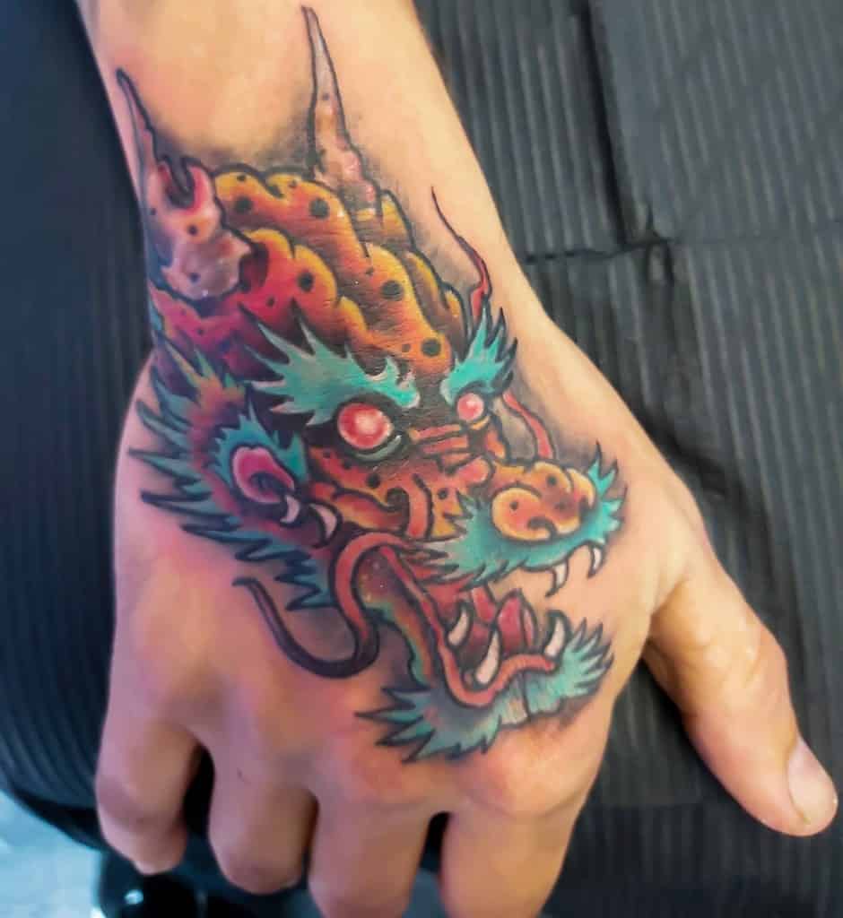 A colorful dragon tattoo adorns the hand, with its head vividly showcased in vibrant reds, greens, and blues