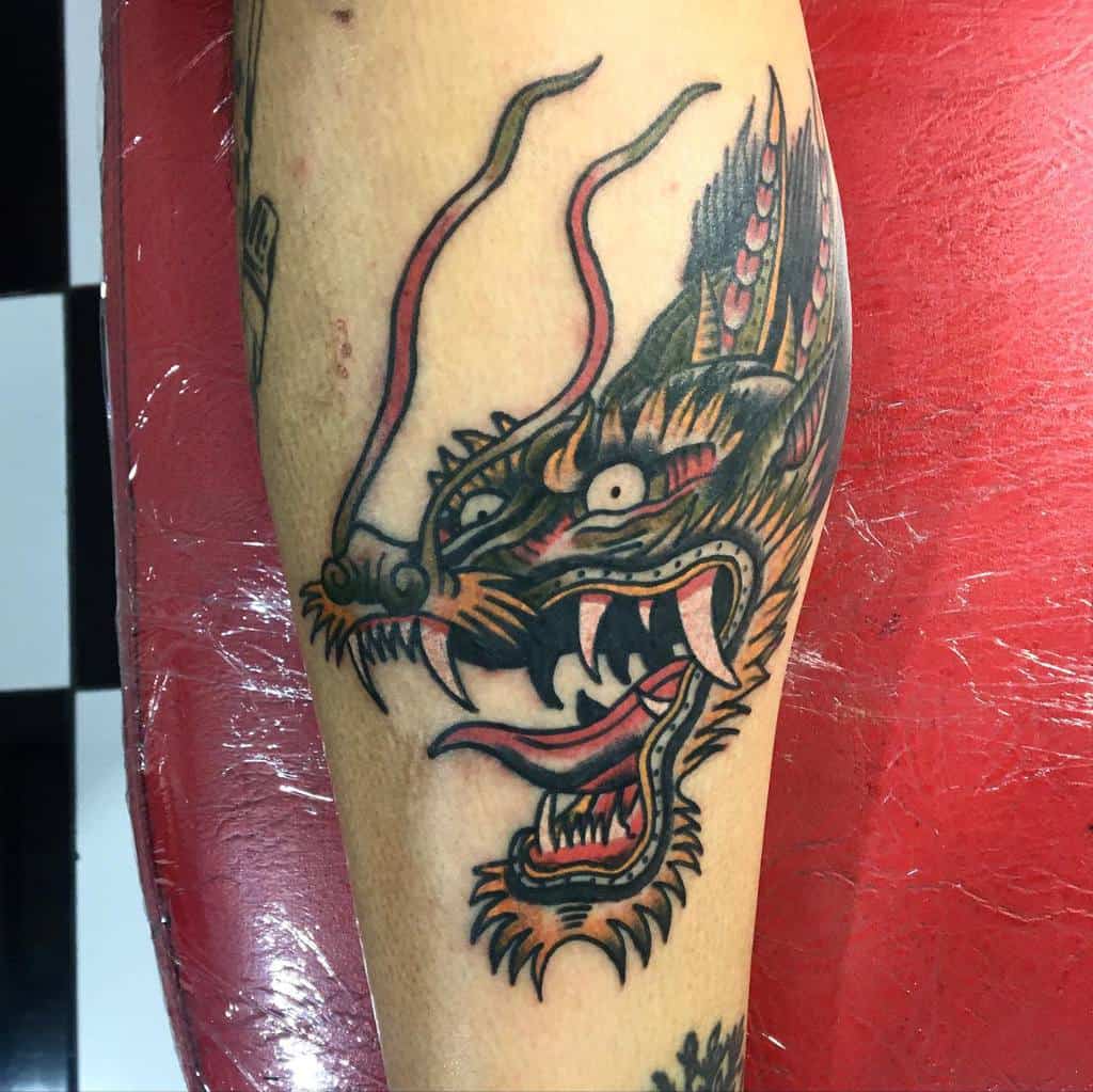 Tattoo of a fierce dragon head on an arm, featuring bold colors and sharp details that highlight the dragon's intricate head