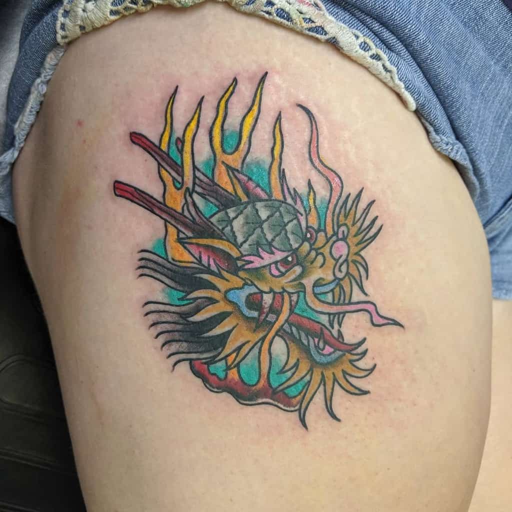 A vibrant dragon tattoo with a strikingly detailed head adorns a person's upper thigh