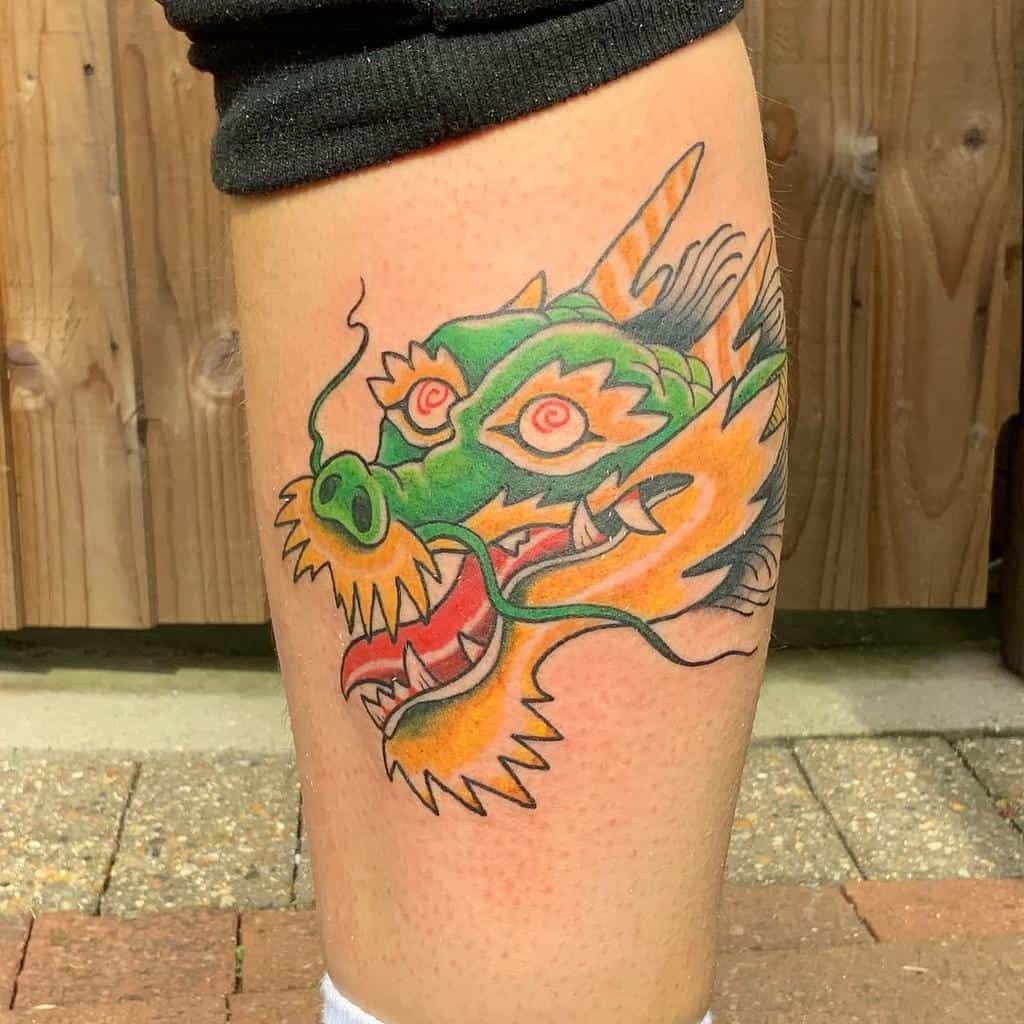 A colorful dragon head tattoo wraps around the calf