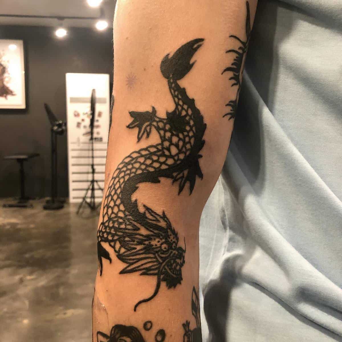 A black dragon tattoo on an inner forearm