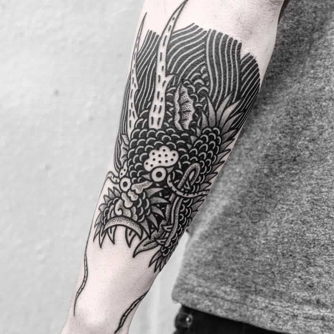 Forearm featuring an intricate black ink dragon tattoo