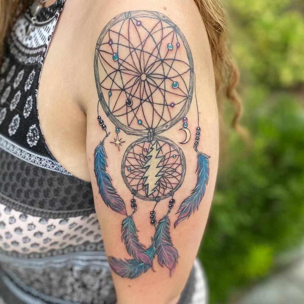 Arm tattoo with dreamcatchers, feathers, and celestial symbols in blue and pink hues