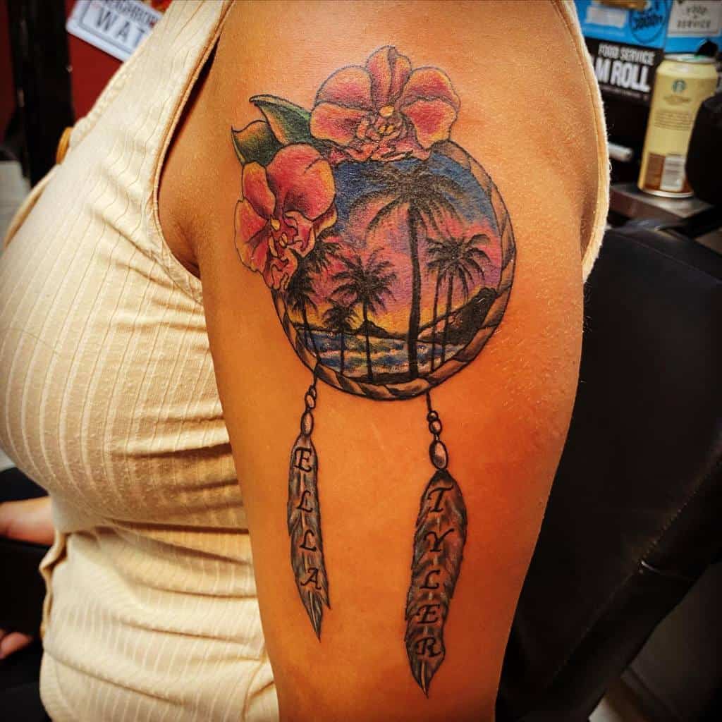 Tattoo of a beach sunset with flowers and feathers labeled "Ella" and "Tyler" on a person's upper arm