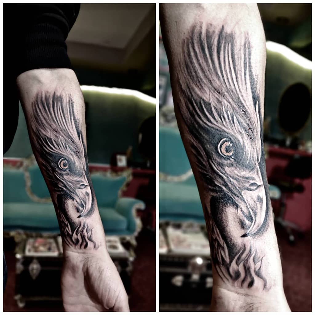 Forearm tattoo of a detailed, dark-shaded eagle with intense eyes and flowing feathers