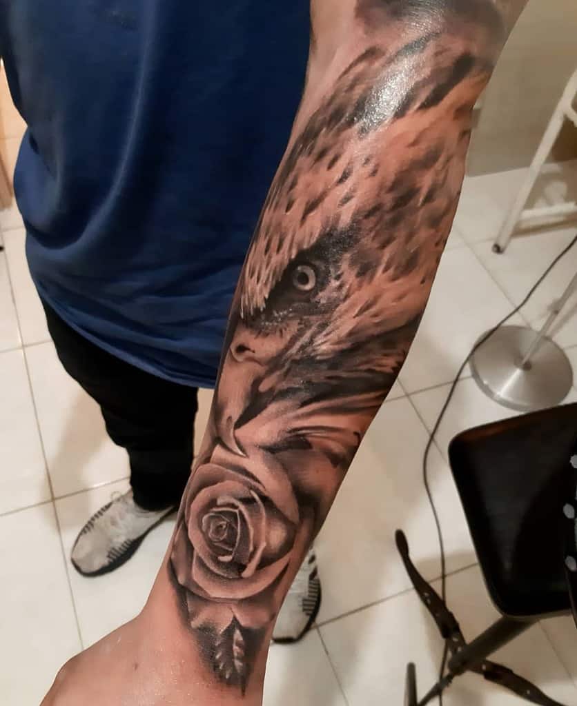 Forearm tattoo with an eagle's head above a detailed rose