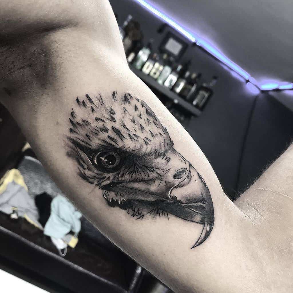 Black and white tattoo of an eagle's head on a bicep