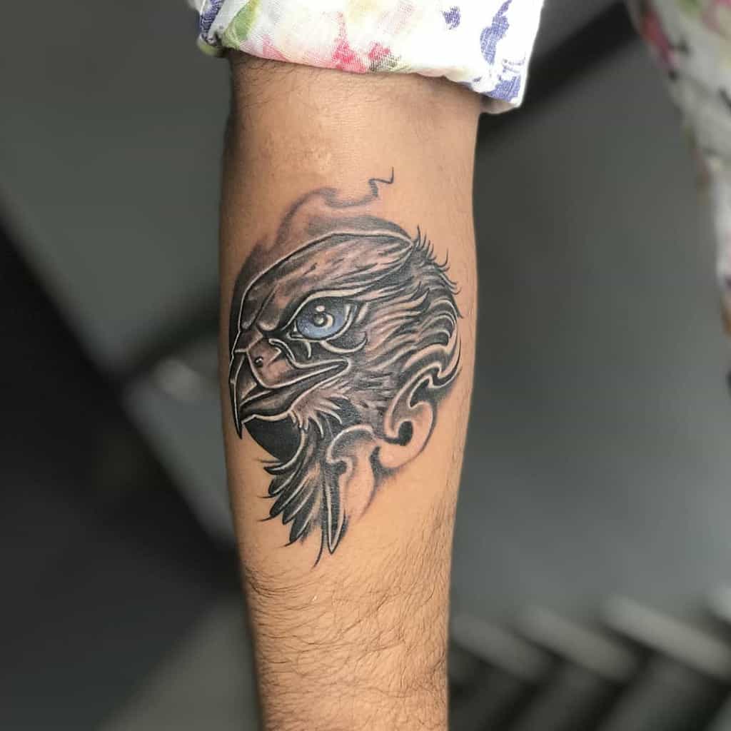 A detailed tattoo of a fierce eagle with a shaded background on a forearm