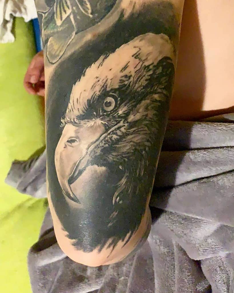 Tattoo of a detailed, fierce-looking eagle's head on an arm