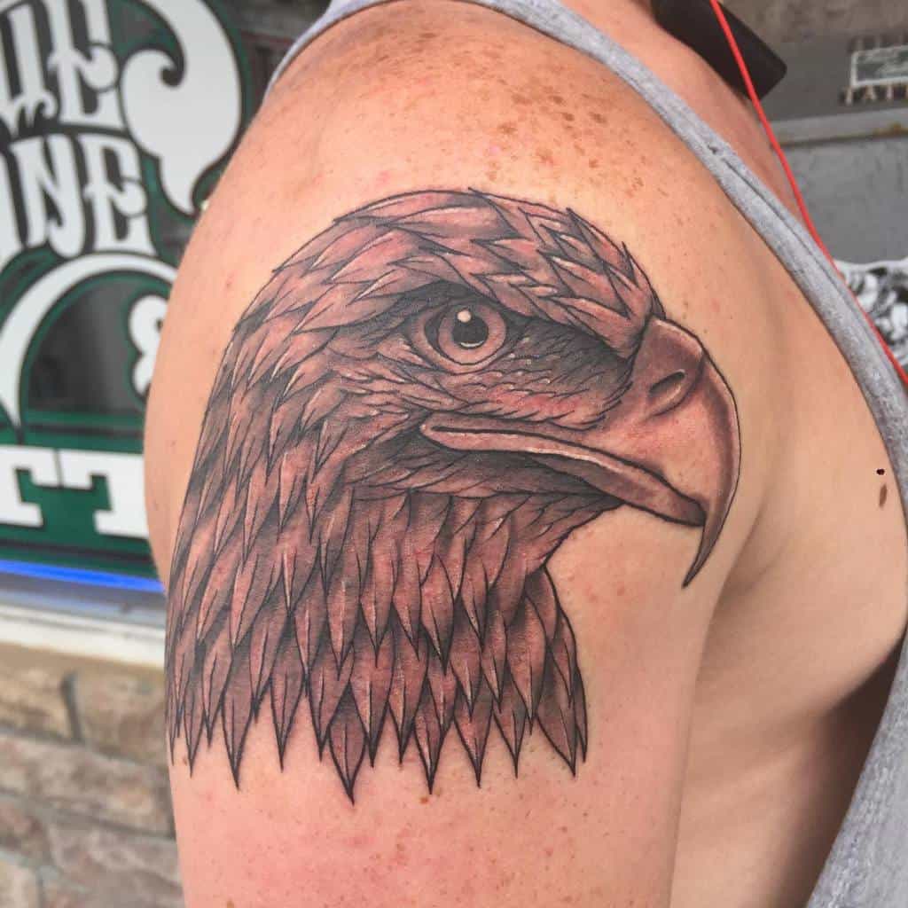 Close-up of an eagle head tattoo on a shoulder with detailed feathers and a fierce expression