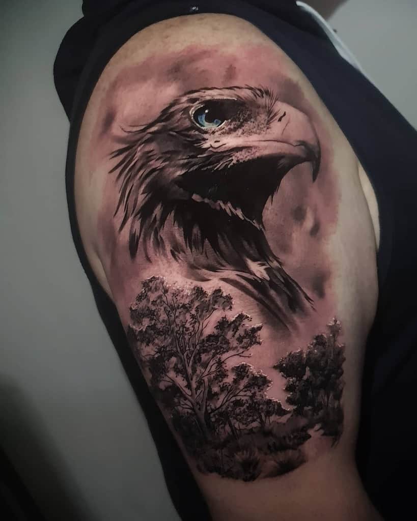 Tattoo of an eagle's head above detailed trees on a shoulder