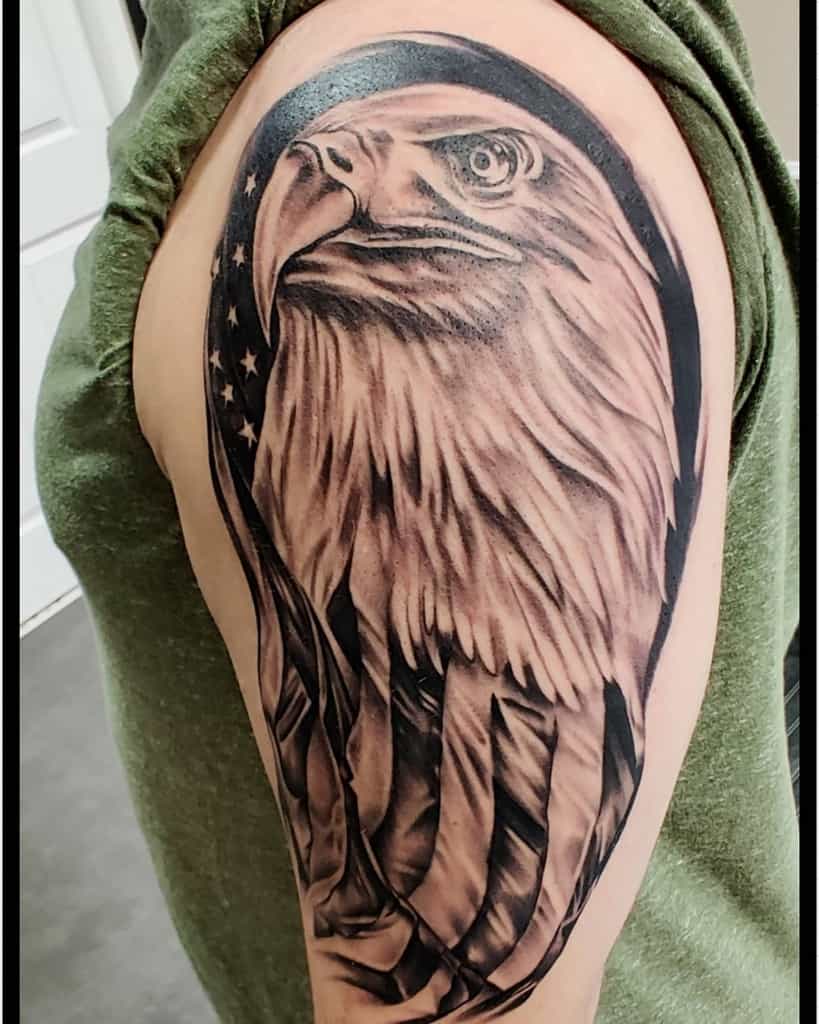 Tattoo of a bald eagle's head with an American flag background on an upper arm