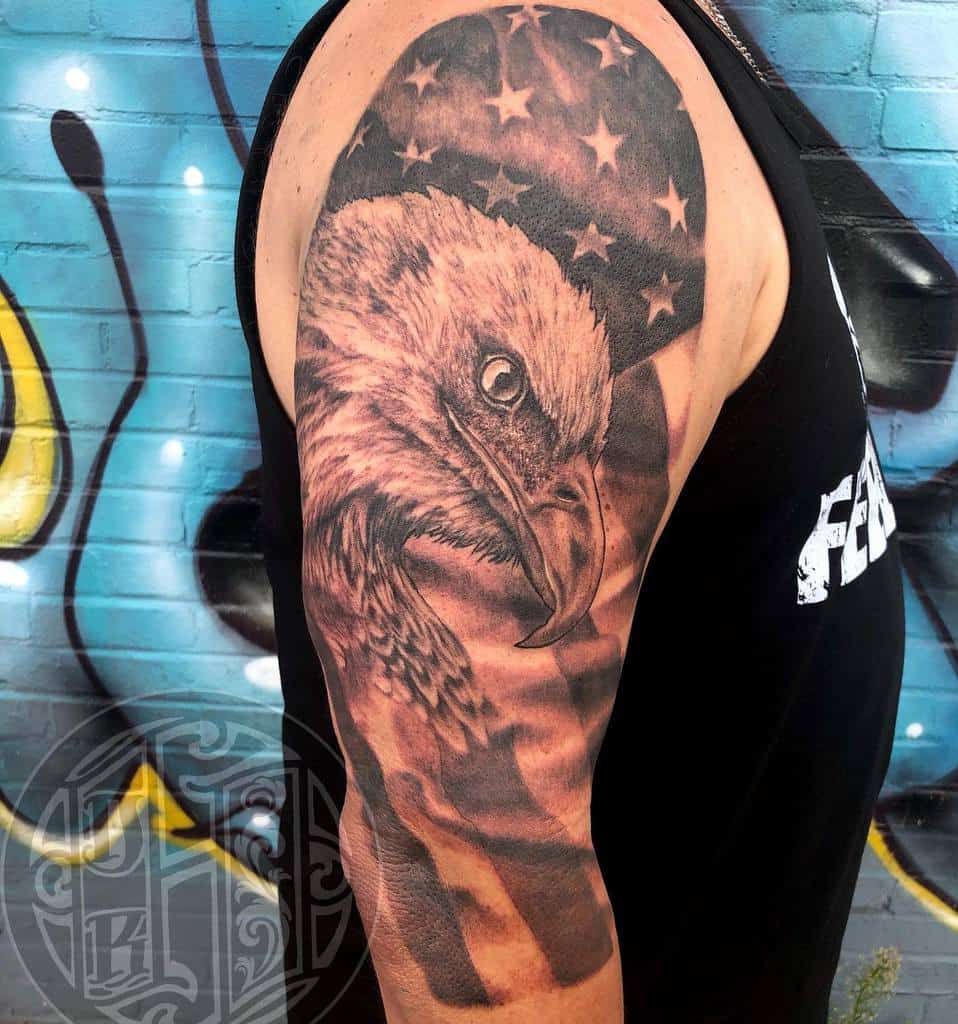 A detailed eagle head tattoo with an American flag an upper arm