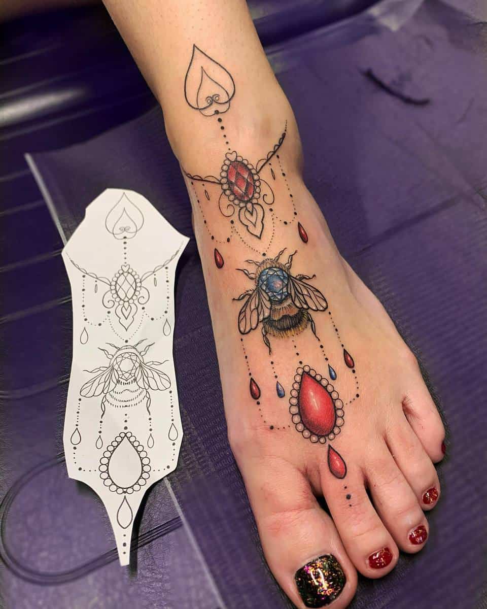 Colorful tattoo of a bee and gemstones on a foot, with a matching stencil design beside it