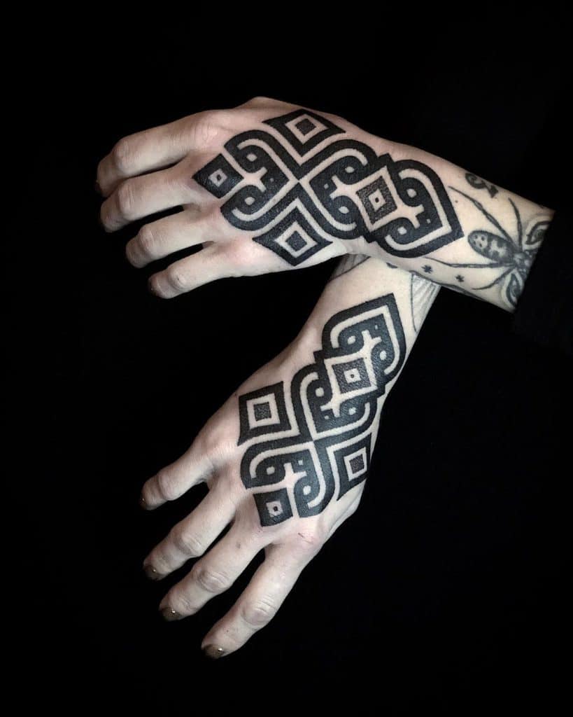 Two hands with intricate black geometric pattern tattoos