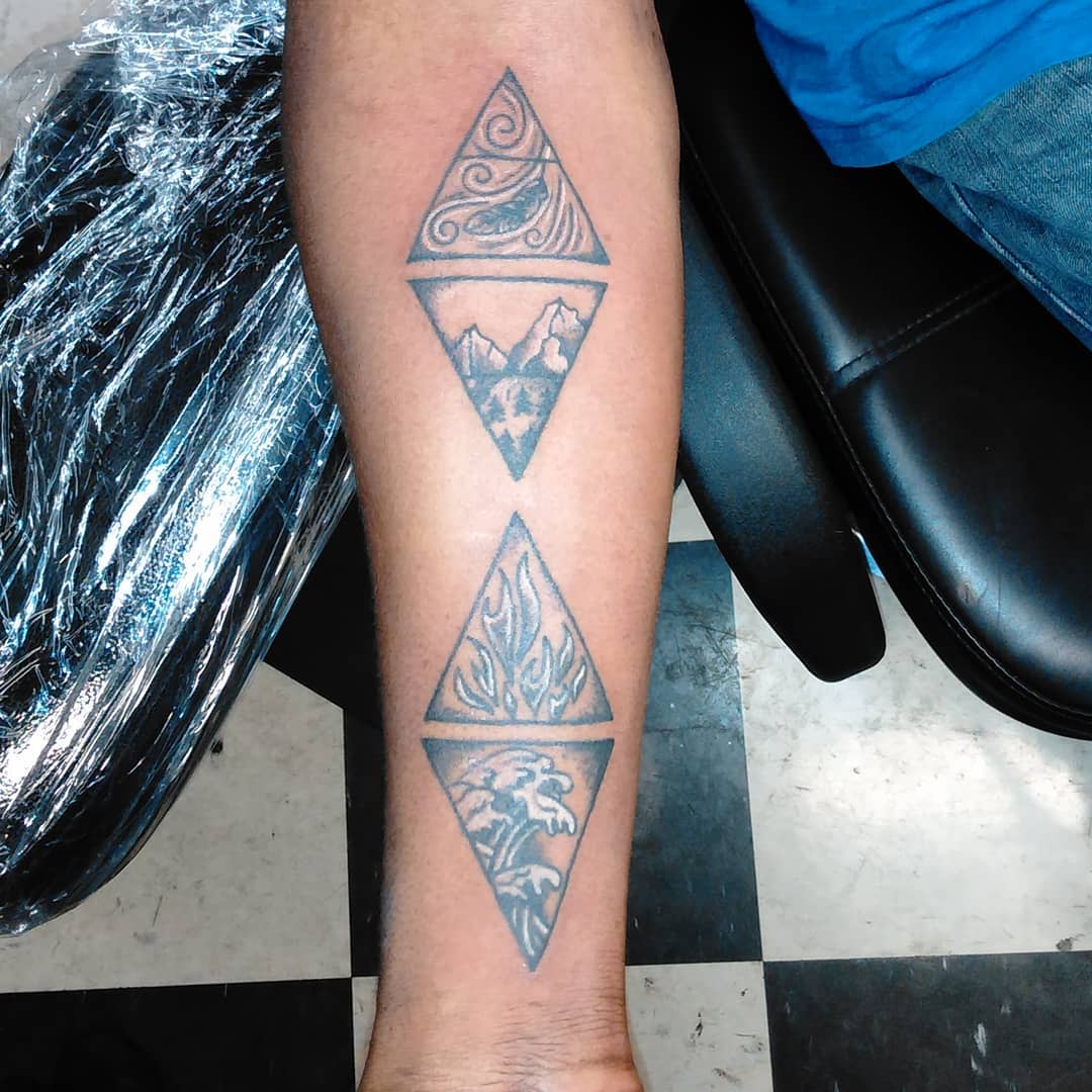 Forearm with three triangle tattoos depicting wind, mountains, flames, and waves