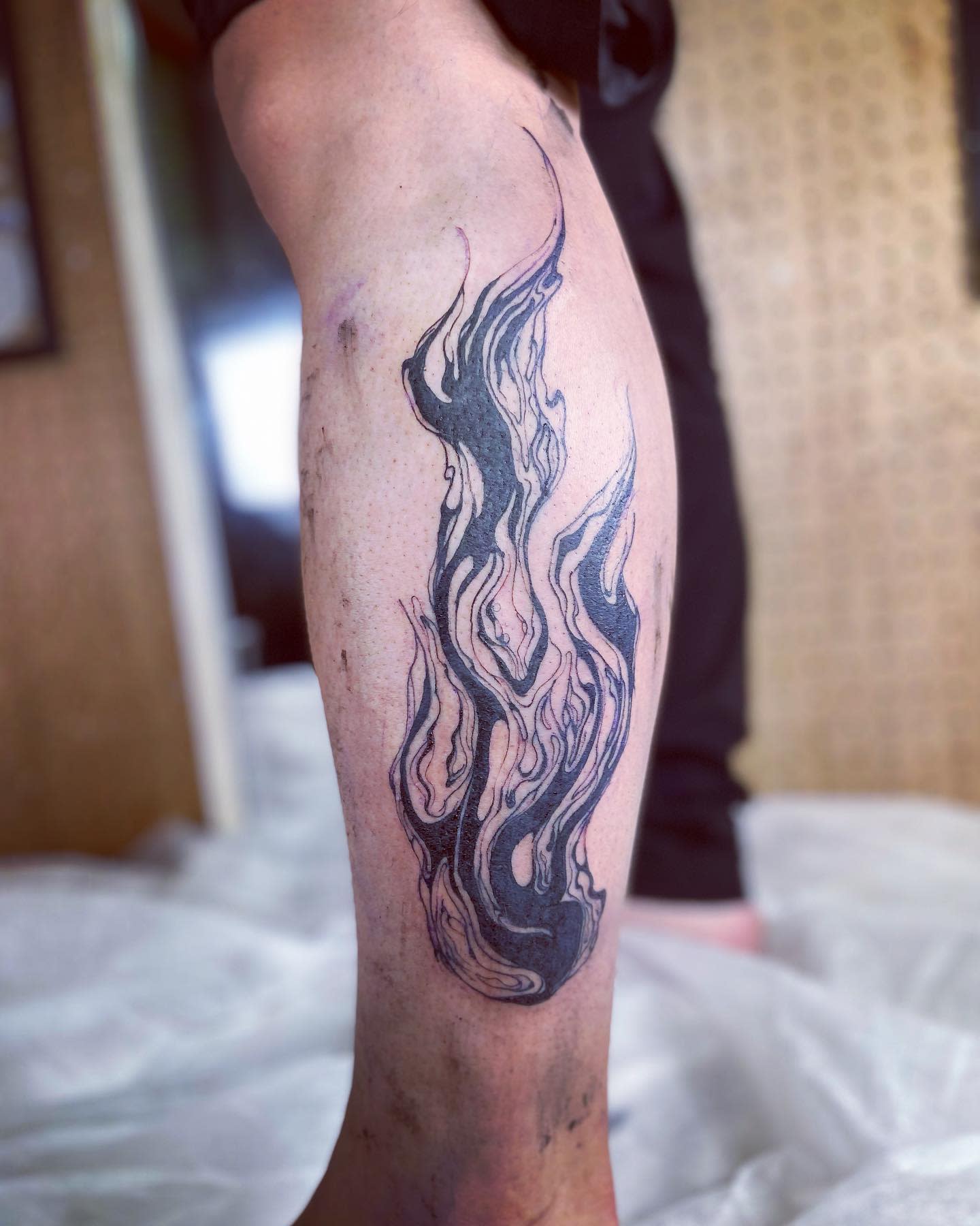 Leg with an abstract, flowing tattoo design in black ink on the calf