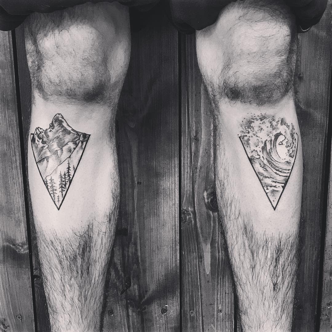 Two legs with triangular tattoos: one depicting mountains, the other depicting an ocean wave