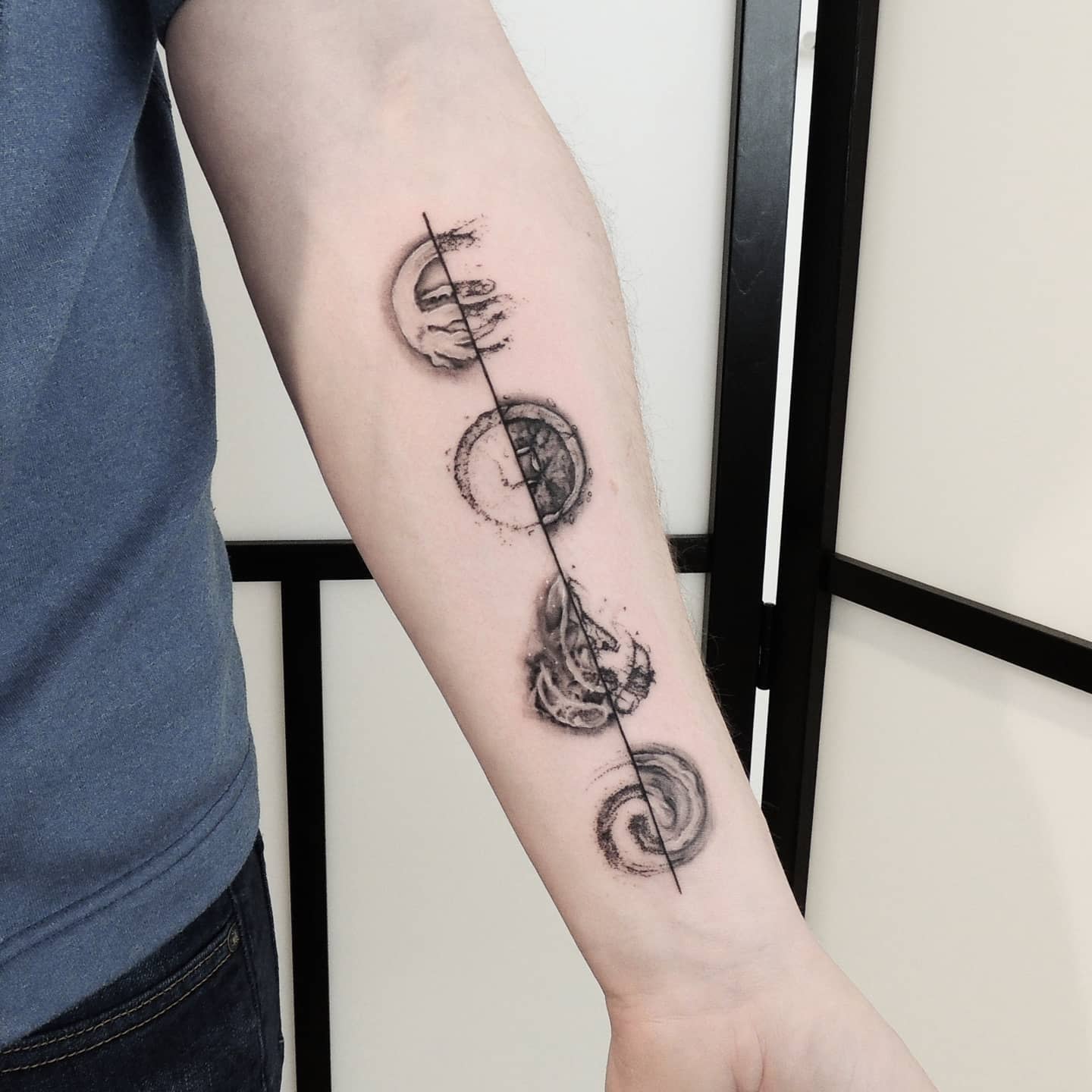 Forearm tattoo featuring four elements circular designs aligned vertically