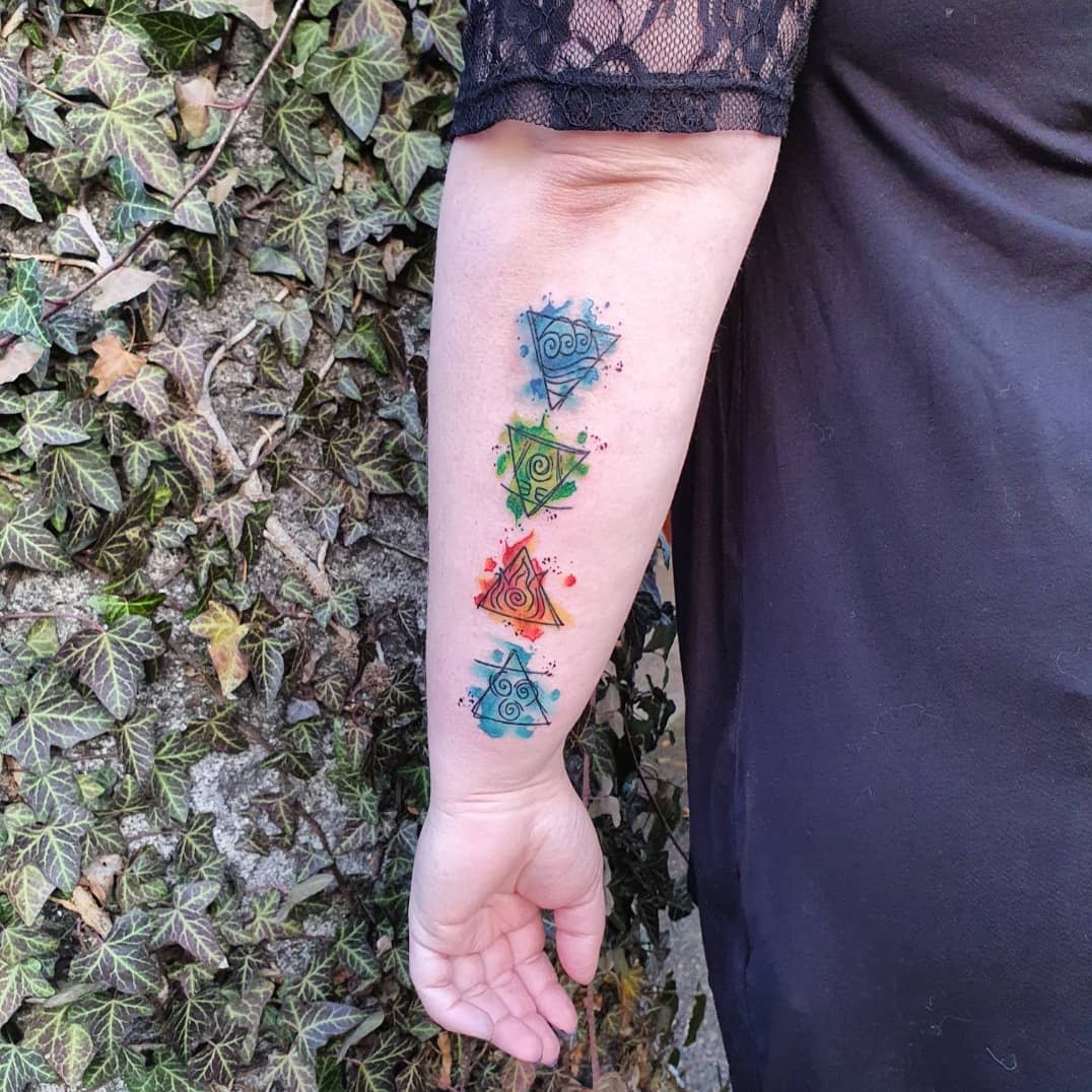 Forearm tattoo of colorful abstract shapes representing four elements on an arm